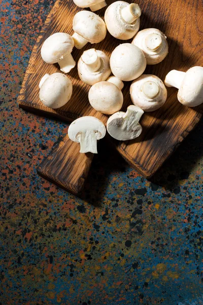 Fresh organic mushrooms on vintage cutting board, vertical
