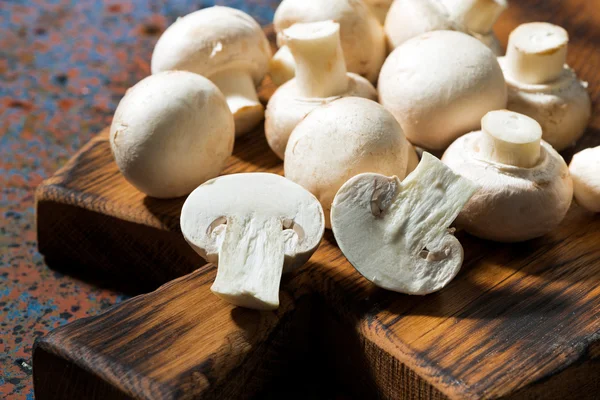 Fresh organic mushrooms on vintage cutting board, closeup