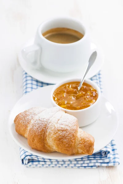 Fresh croissant with orange jam and coffee, vertical