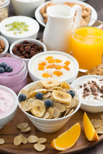 Breakfast buffet with cereals, yoghurt and fruit on wooden tray
