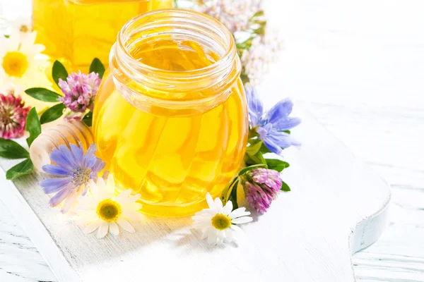 Jars with fresh flower honey on white background, top view