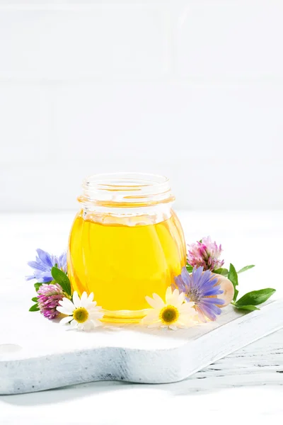 Jar with fresh flower honey and white wooden background
