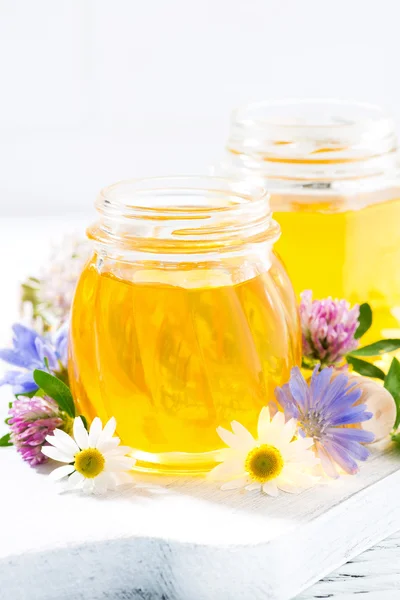 Jars with fresh flower honey on white background, vertical