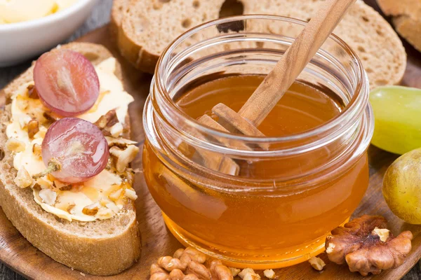 Flavored honey, bread with butter and grapes, close-up, top view