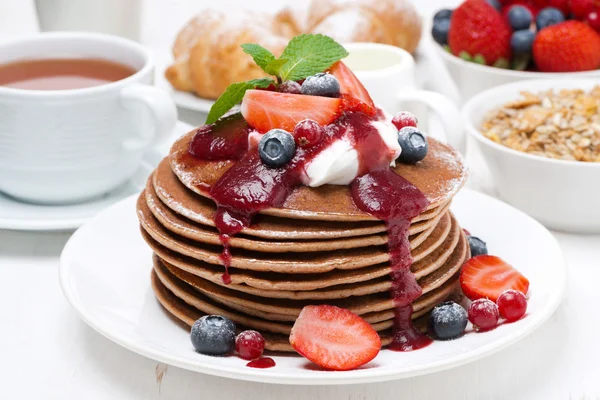 Breakfast with pancakes, cream, fruit sauce and fresh berries