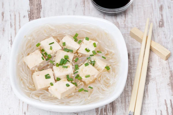 Soup with rice noodles, tofu and green onions, top view