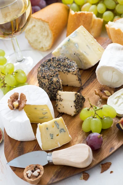 Cheese platter, snacks, bread and wine, vertical