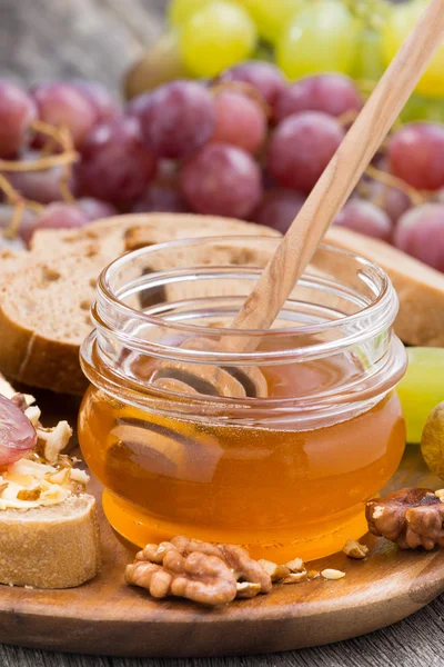 Flavored honey, bread with butter and grapes, vertical, close-up