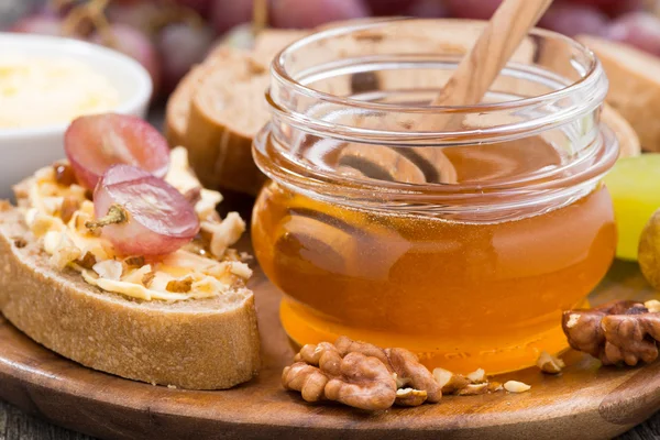 Flavored honey, bread with butter and grapes, close-up