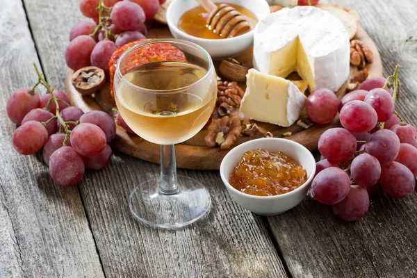 Glass of cold white wine and snacks on a wooden table