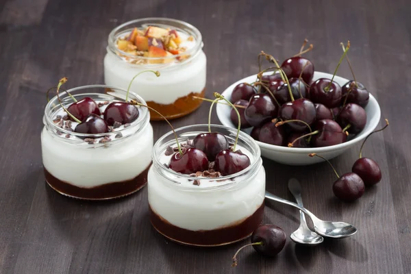 Dessert with cream and jam in glass jar on wooden table
