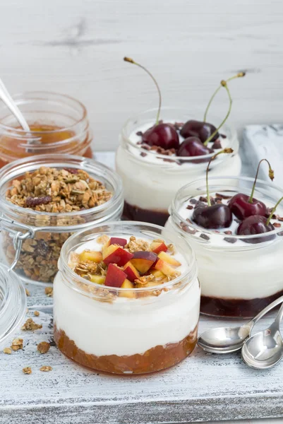 Dessert with cream, peach and cherry jam in glass jars