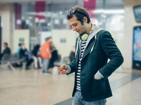 Man in casual clothing looking at his telephone inside a station