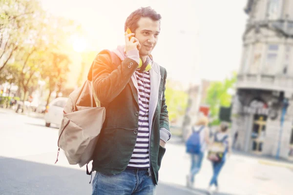 Urban man casual clothing in the city calling under the sun with sun flare around him