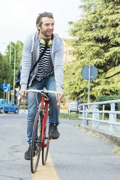 Young adult man riding a bike in the city street