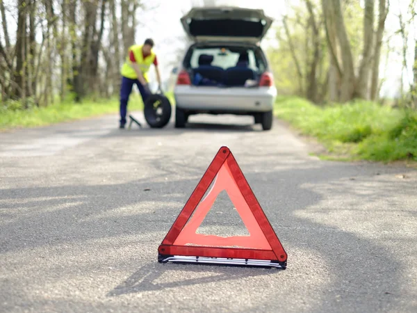 Man fixing flat tire after a vehicle breakdown problem