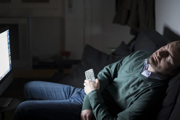 Man sleeping and snoring in front of television on the couch