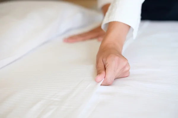 Hands of hotel maid making a room bed