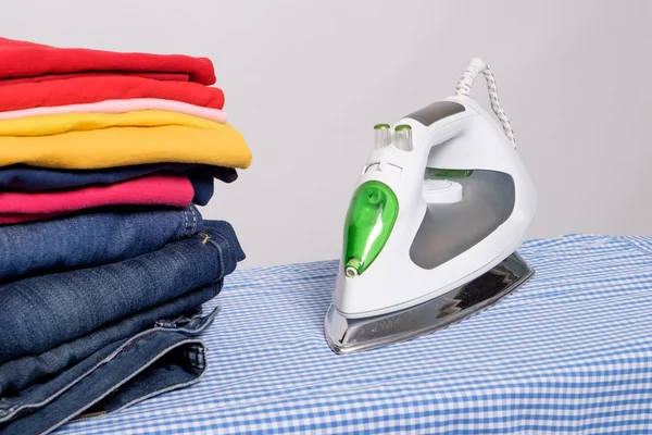 Iron next to pile of clothes isolated