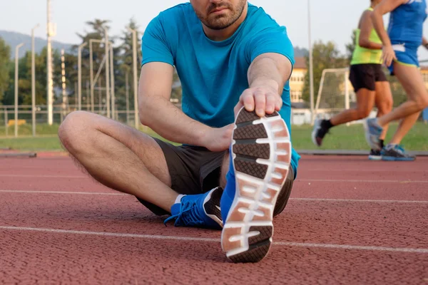 Runner making stretching on the track