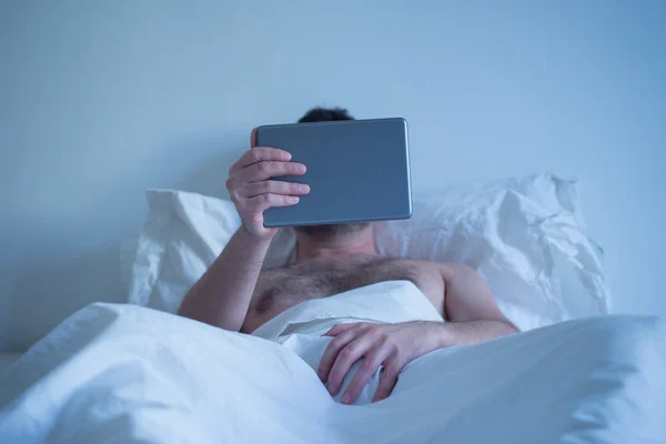 Man lying in the bed , watching porn on the tablet and masturbat