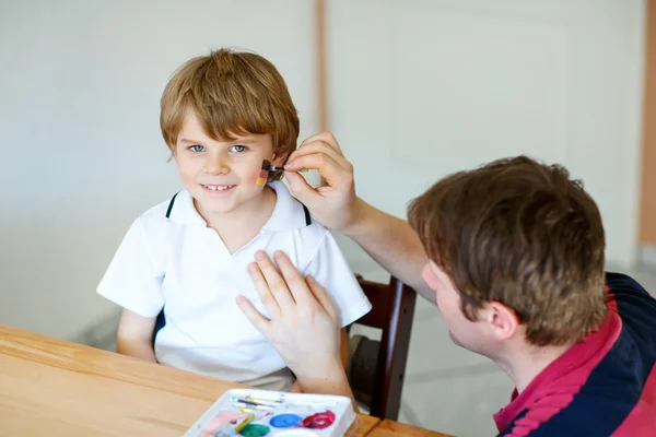 Dad painting flag on face of little kid for football or soccer