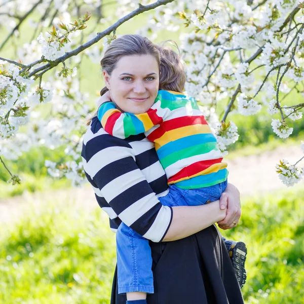 Young mum and little kid boy in blooming garden