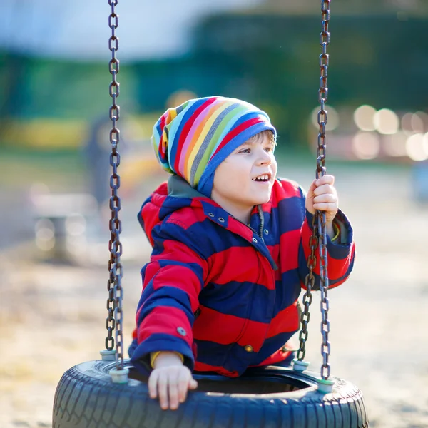 Little kid boy having fun on chain swing outdoors