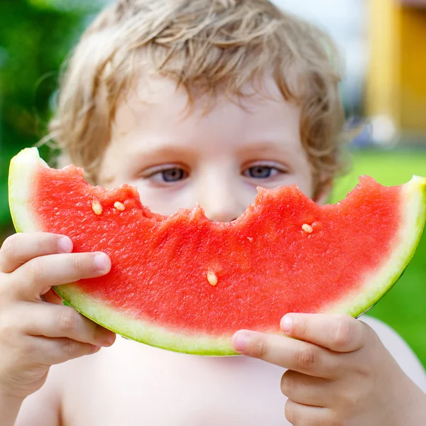 Little toddler boy  eating healthy watermelon in summer