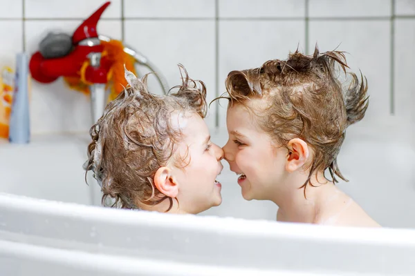 Two little boys playing together in bathtub