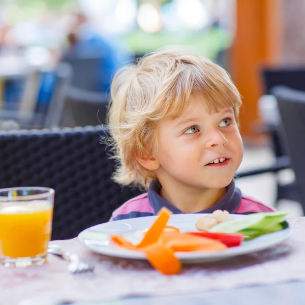 Little kid boy having healthy breakfast in restaurant