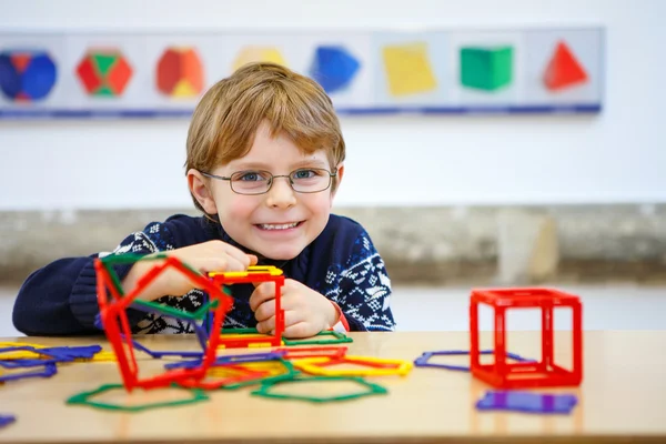 Little kid boy building geometric figures with plastic blocks