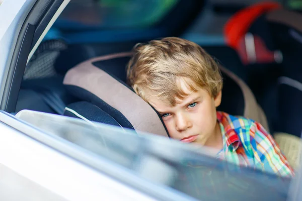 Sad tired kid boy sitting in car  during traffic jam