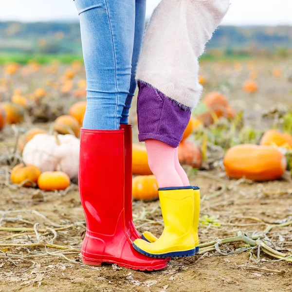 Legs of young woman and her little girl daugher in rainboots.