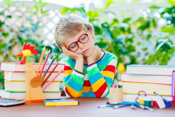 Sad school kid boy with glasses and student stuff