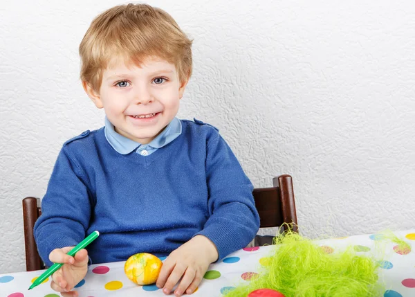 Little toddler boy painting colorful eggs for Easter hunt