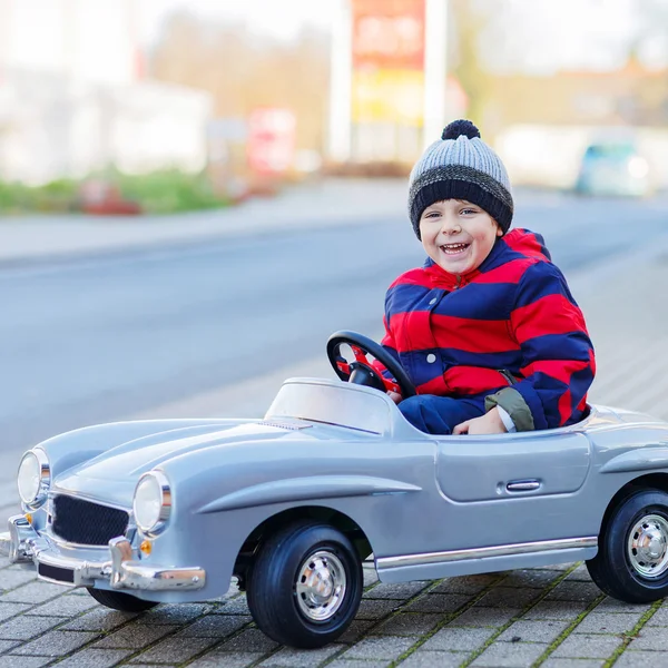 Happy little boy driving big toy car and having fun, outdoors