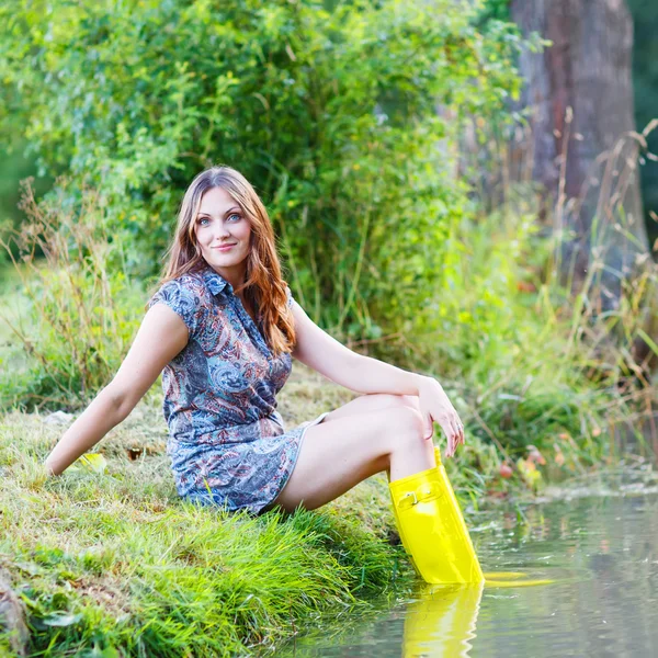 Young beautiful woman sitting in yellow rain rubber boats by a r
