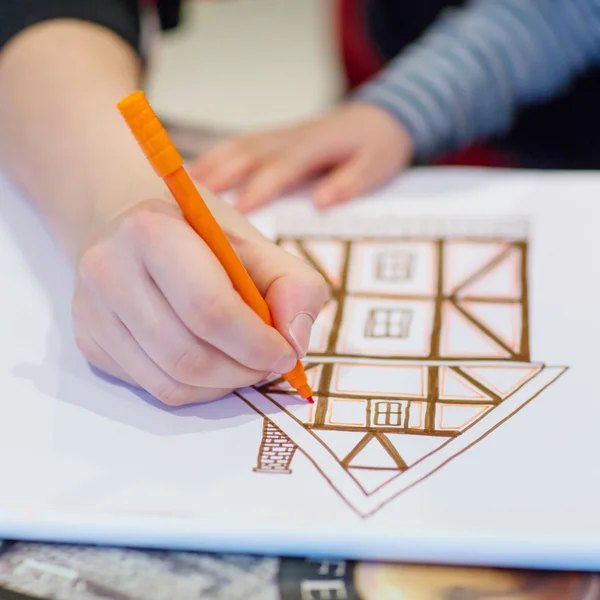 Hands of dad and little child drawing  picture of house