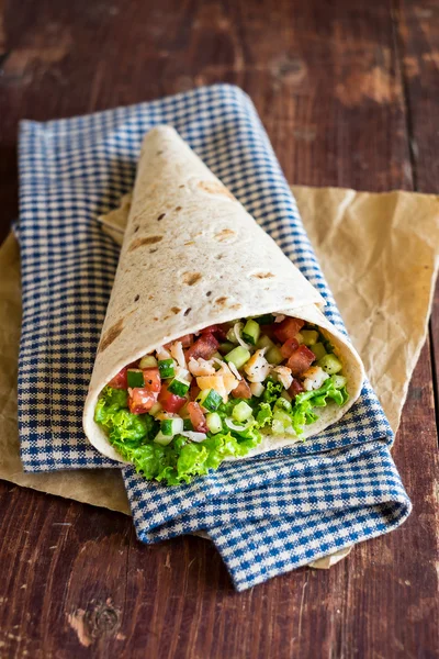 Mexican style tortilla wrap with shrimps, tomatoes, cucumbers, onion on a wooden table for a snack or summer picnic, selective focus
