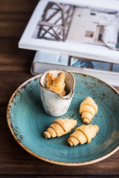 Homemade freshly baked short crust pastry crescent rolls cookies with sugar on a plate on a wooden rustic dark brown table, selective focus