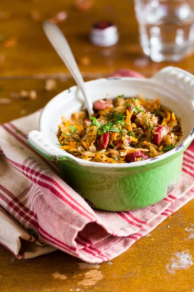 White cabbage stew with chopped carrot, onion, tomato sauce, green lentil and sausages in a hot pot ready to serve for lunch and dinner