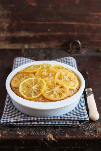Citrus cake with lemon caramel slices on top in a baking dish on a wooden table, selective focus