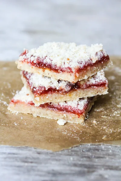 Stack of cake or cookies with plum, strawberry, raspberry and cherry jam or marmalade with sweet crumbs, cinnamon and nuts on a parchment paper