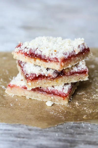 Stack of cake or cookies with plum, strawberry, raspberry and cherry jam or marmalade with sweet crumbs, cinnamon and nuts on a parchment paper