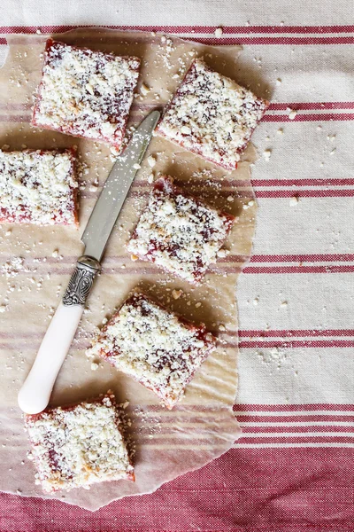 Stack of cake or cookies with plum, strawberry, raspberry and cherry jam or marmalade with sweet crumbs, cinnamon and nuts on a parchment paper, selective focus