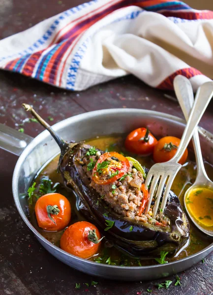 Stuffed eggplant or aubergine with minced meat, carrot, onion, cherry tomatoes, pepper in a pan, traditional turkish cuisine, selective focus