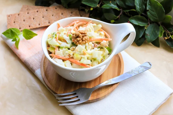 Fresh salad with white cabbage, carrot, apples and pears with walnuts and yogurt dressing in a bowl, selective focus