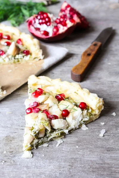 Puff pastry pie with fish cod fillet, spinach, dill, pomegranate seeds and cream cheese, selective focus