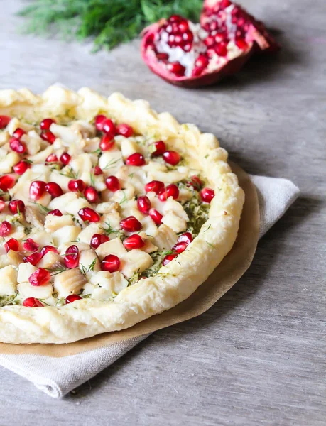 Puff pastry pie with fish cod fillet, spinach, dill, pomegranate seeds and cream cheese, selective focus